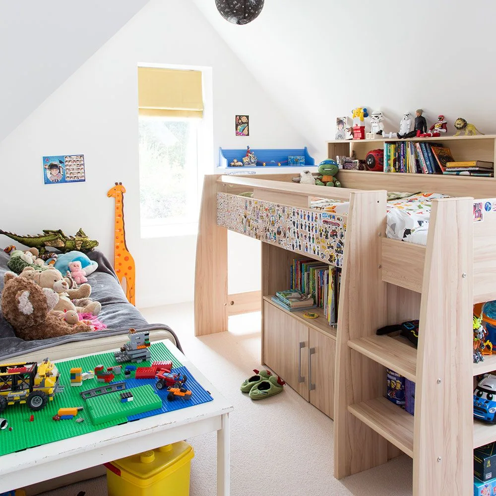 Raised wood bed with open toy and book shelves beside a table holding construction projects