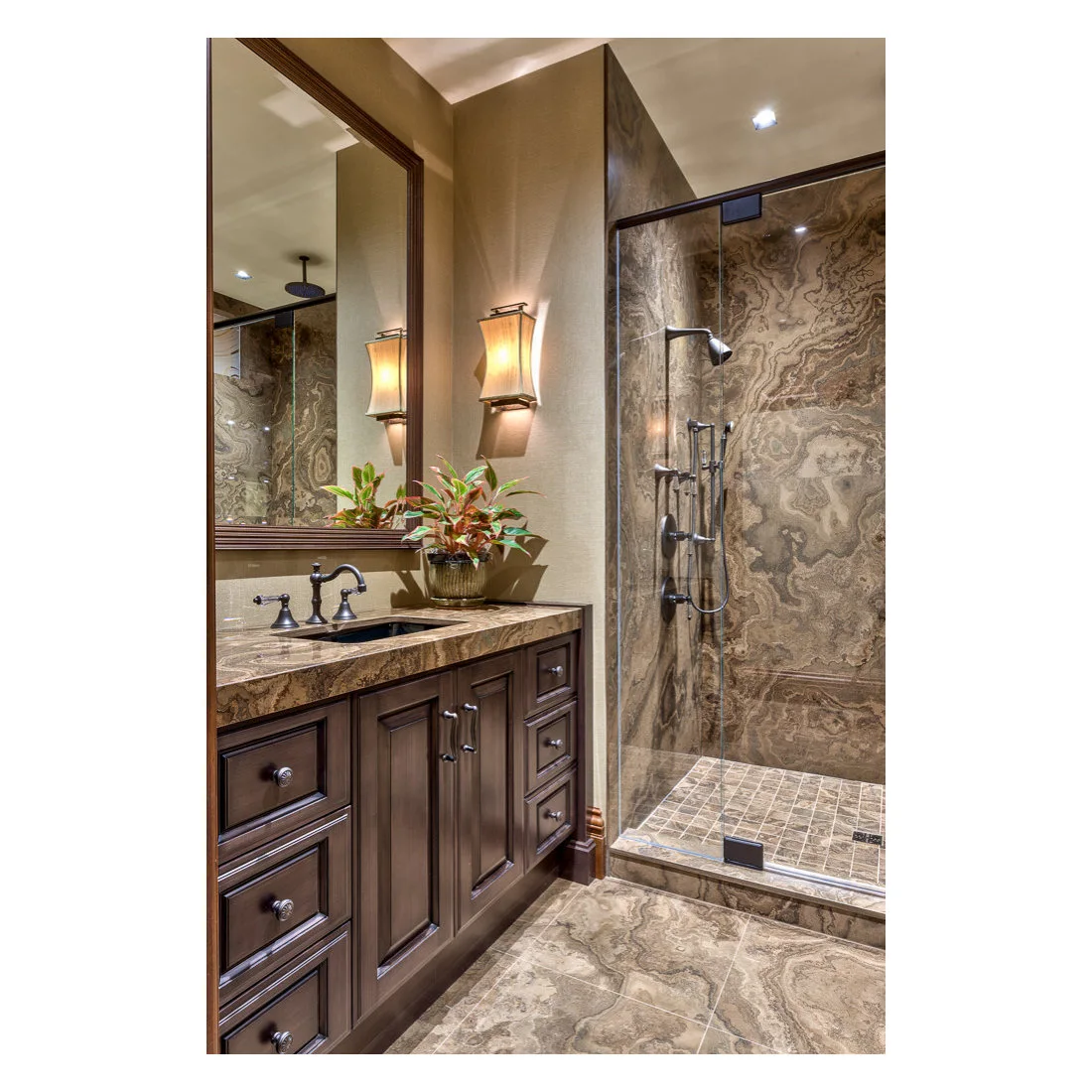 A dark wood vanity beside a shower lined with strongly patterned brown stone surfaces