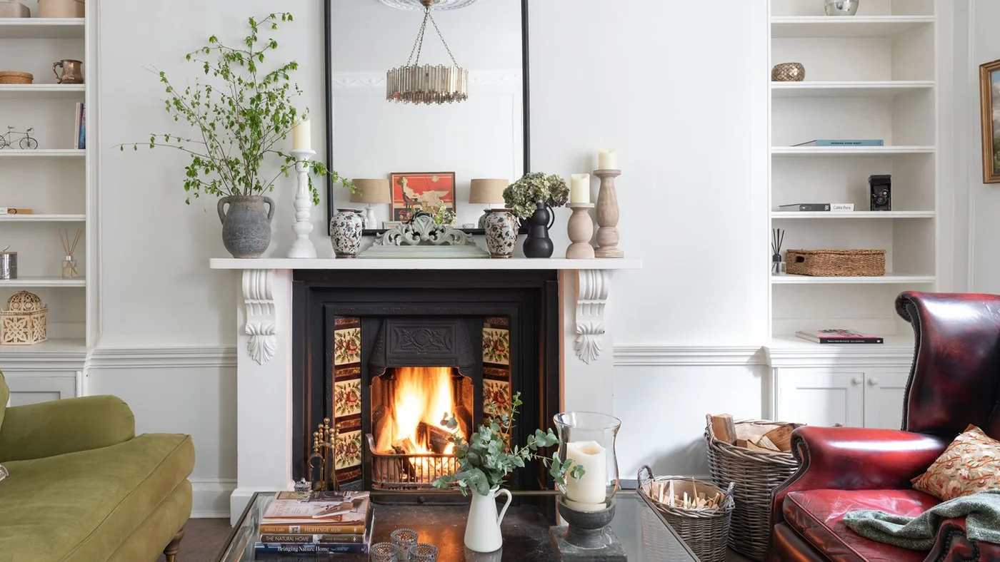 A white mantel frames a black fireplace insert with floral side tiles between pale alcove cupboards.