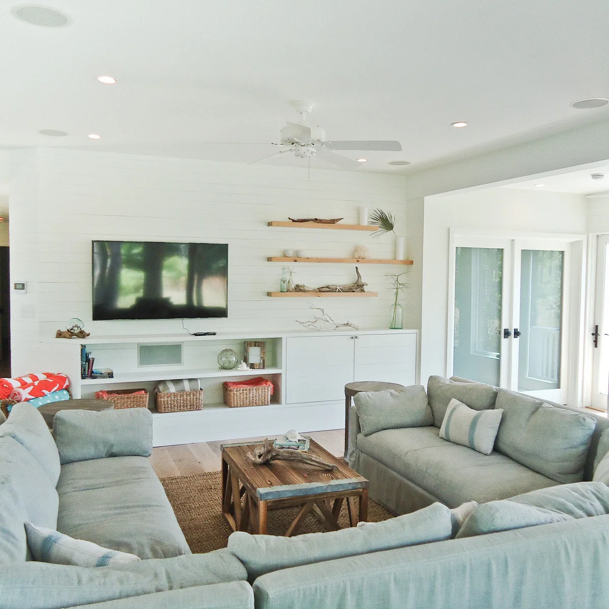 White paneled living room with low cabinets, basket storage and pale grey seating