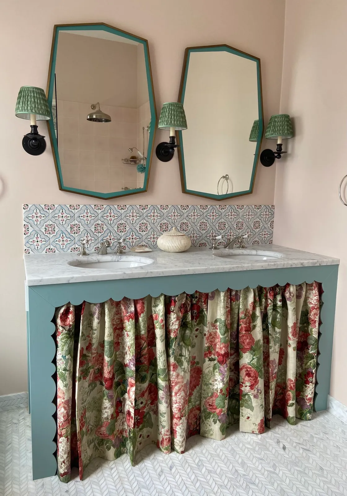 A floral fabric skirt hangs below a pale counter under green-framed mirrors.