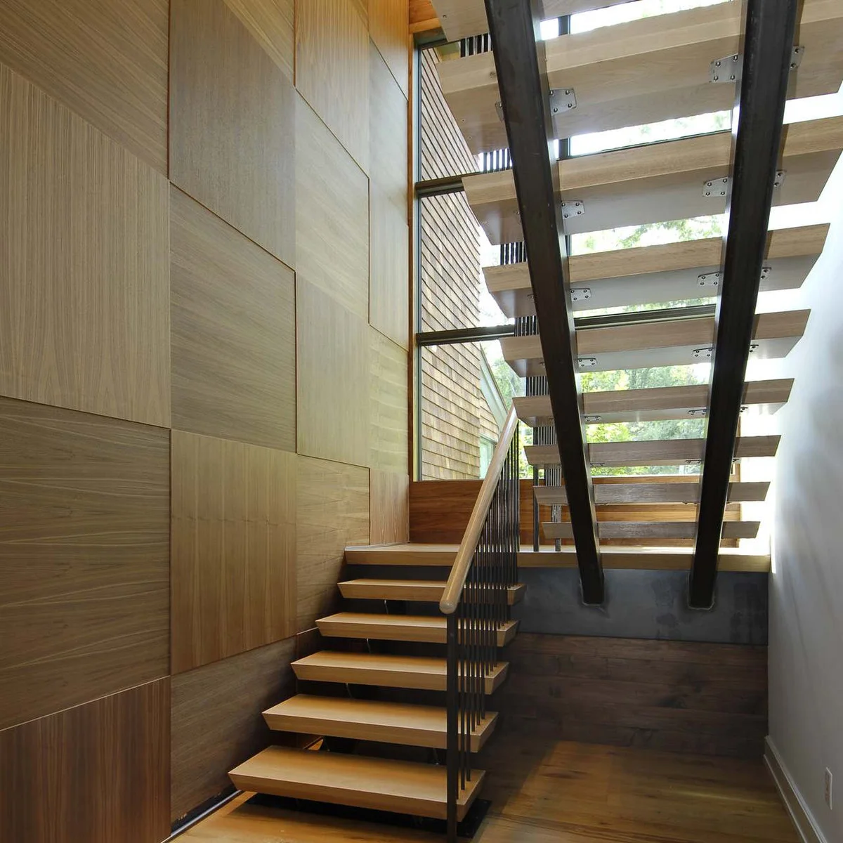 Large wood wall panels alternate grain direction behind an open staircase with dark supports.