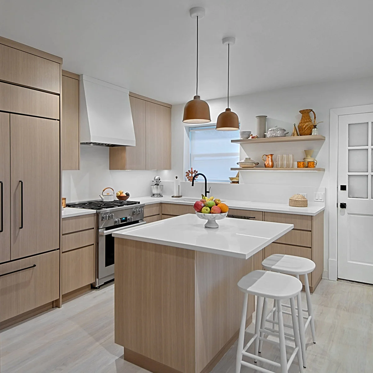 Compact pale wood kitchen island matching flat-front perimeter cabinets with white stools
