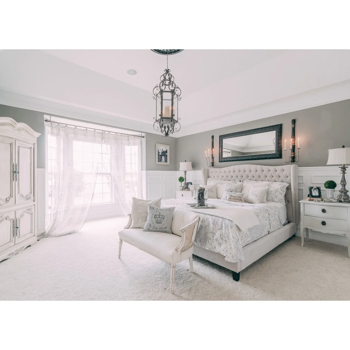 Grey upper bedroom walls above white panels with a tufted pale bed and white furniture