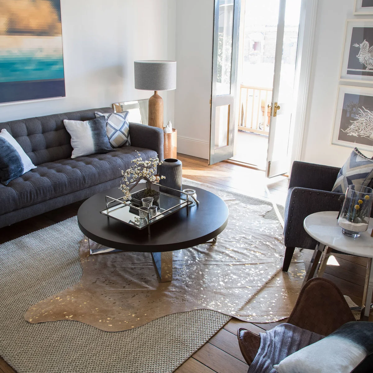 Inner-city terrace living room with gray seating, dark round table and entrance doors beyond