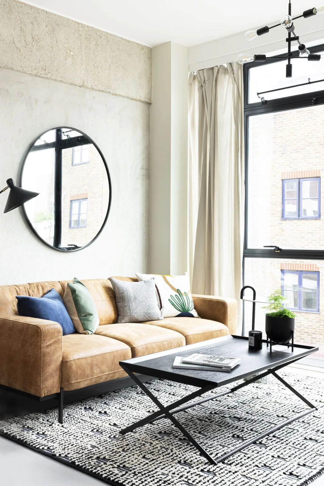 Black rectangular coffee table with books, a candle and a small raised plant pot