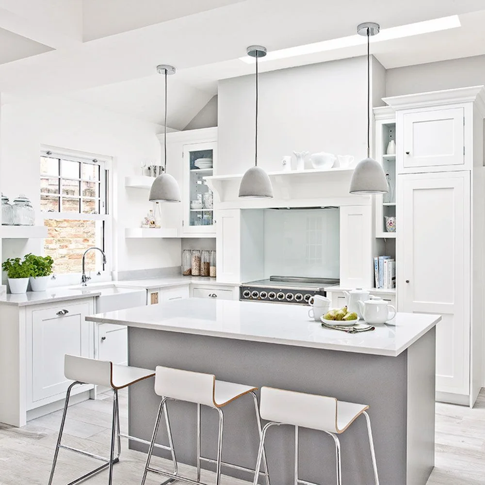 White framed cabinets include a tall pantry and narrow open shelves beside a range, with a pale gray island in front.