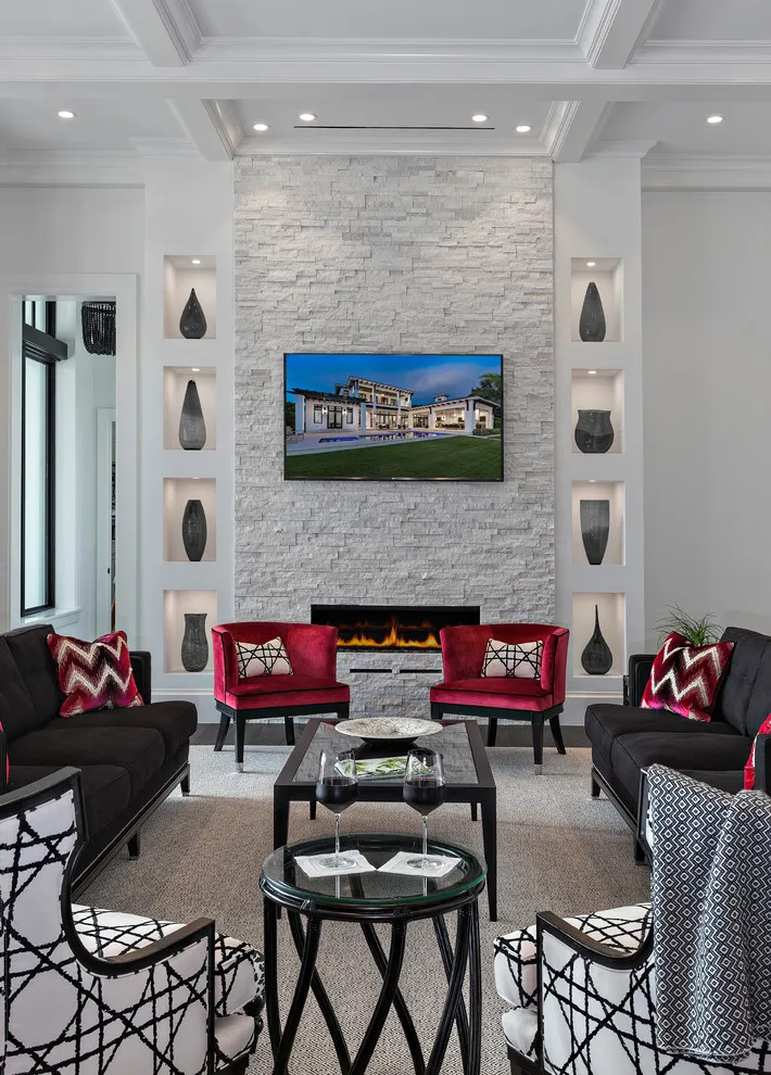 A pale stone fireplace wall rises behind a group of dark and red chairs