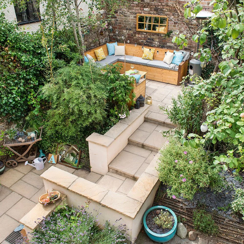 Steps connect two paved courtyard levels with planted retaining edges and corner seating above