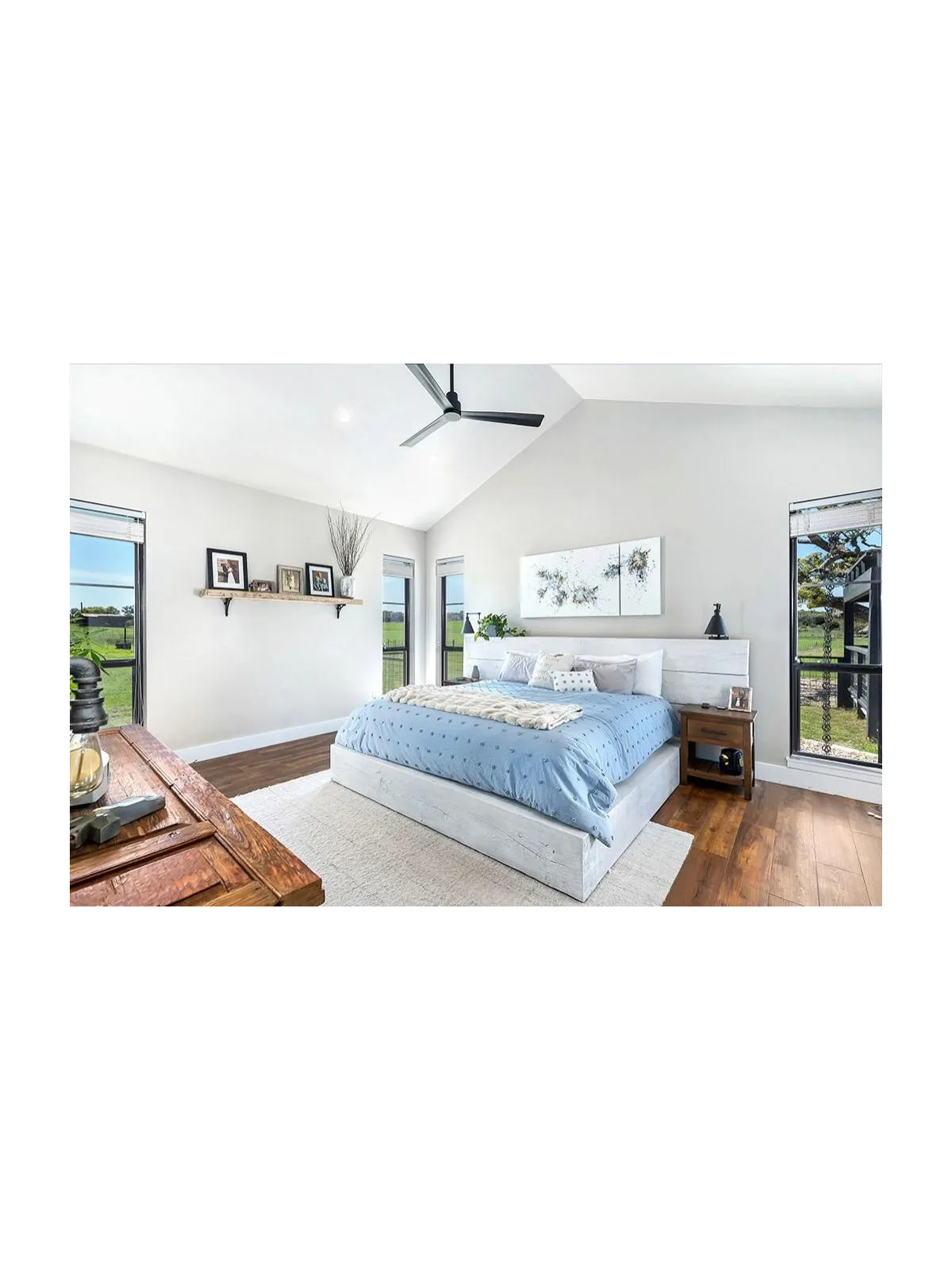 Blue bedding sits against pale walls in a room with timber floors and broad windows.