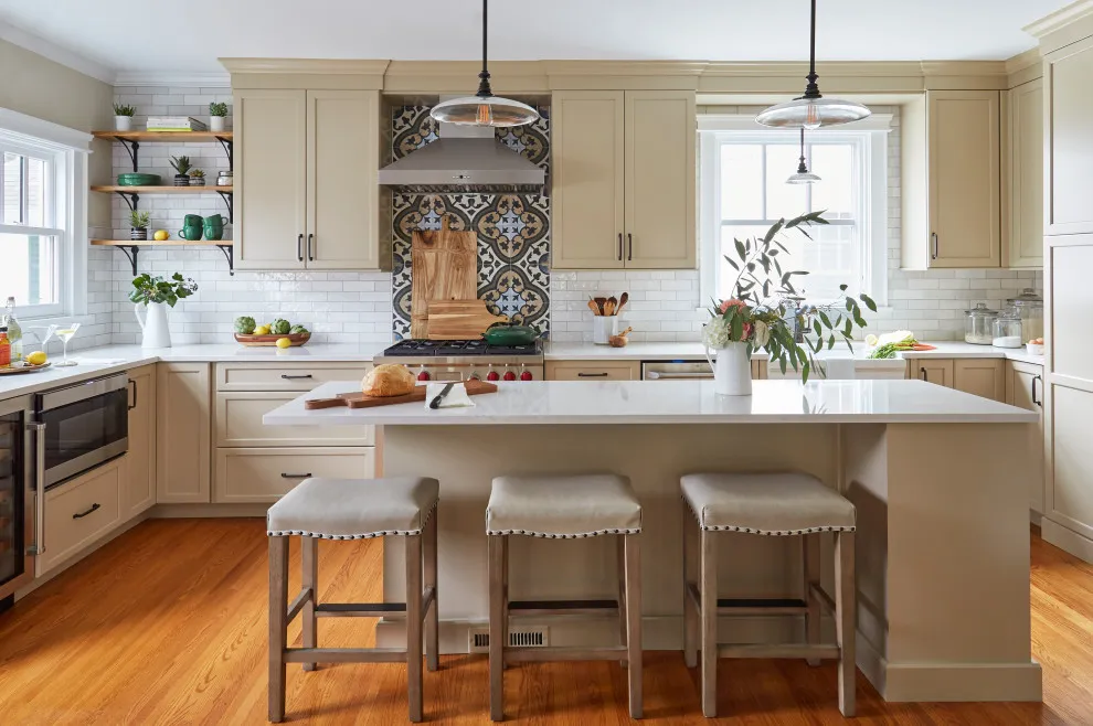Beige perimeter cabinets surround a white island with three stools