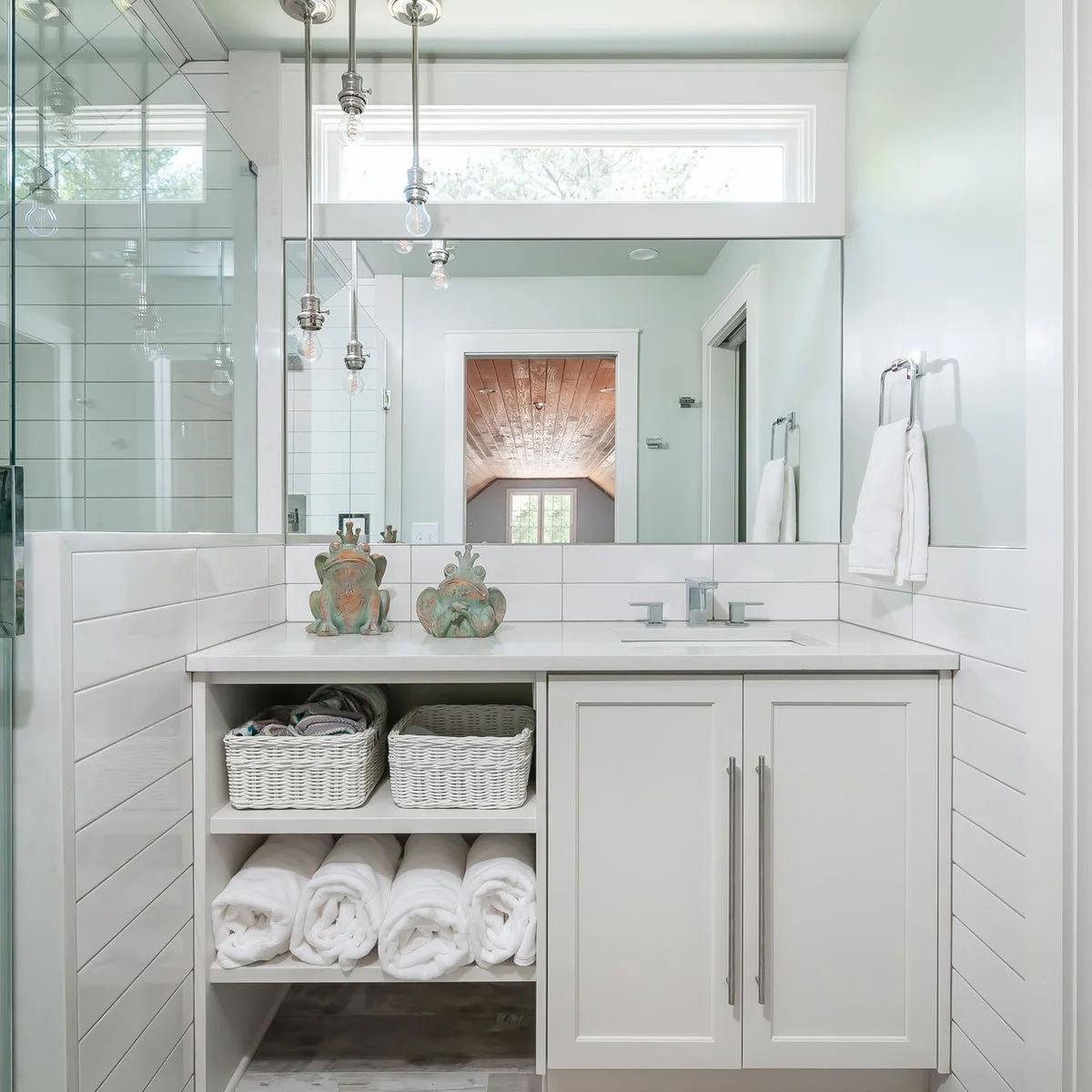 A rectangular chrome towel holder sits on the side wall above a tiled backsplash beside a pale bathroom vanity.