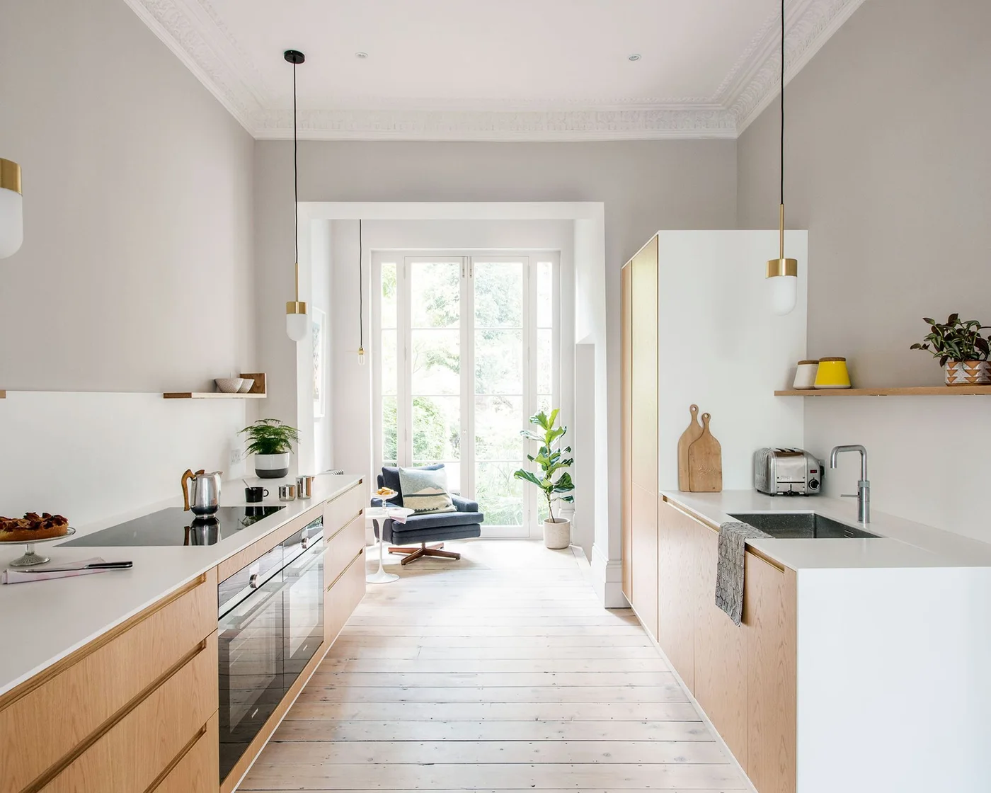 Pale wood and white galley kitchen with slim shelves and small pendant lights