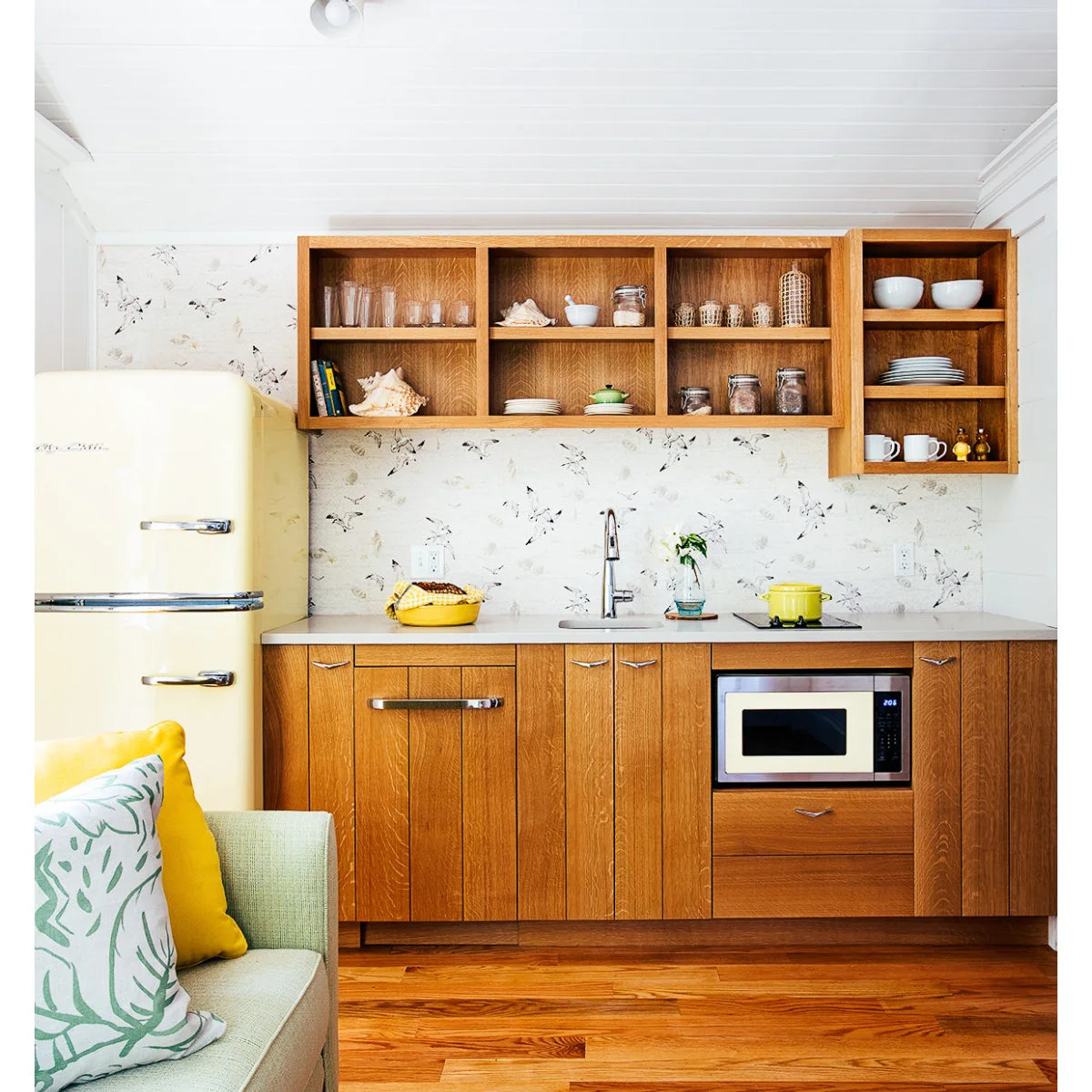 Wood kitchenette with a yellow refrigerator, small cooktop and microwave below the counter
