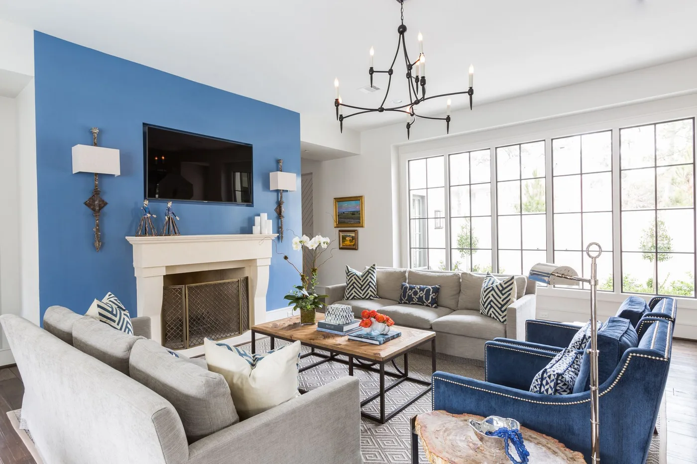 Blue fireplace wall with white mantel and television beside facing pale sofas and blue chairs