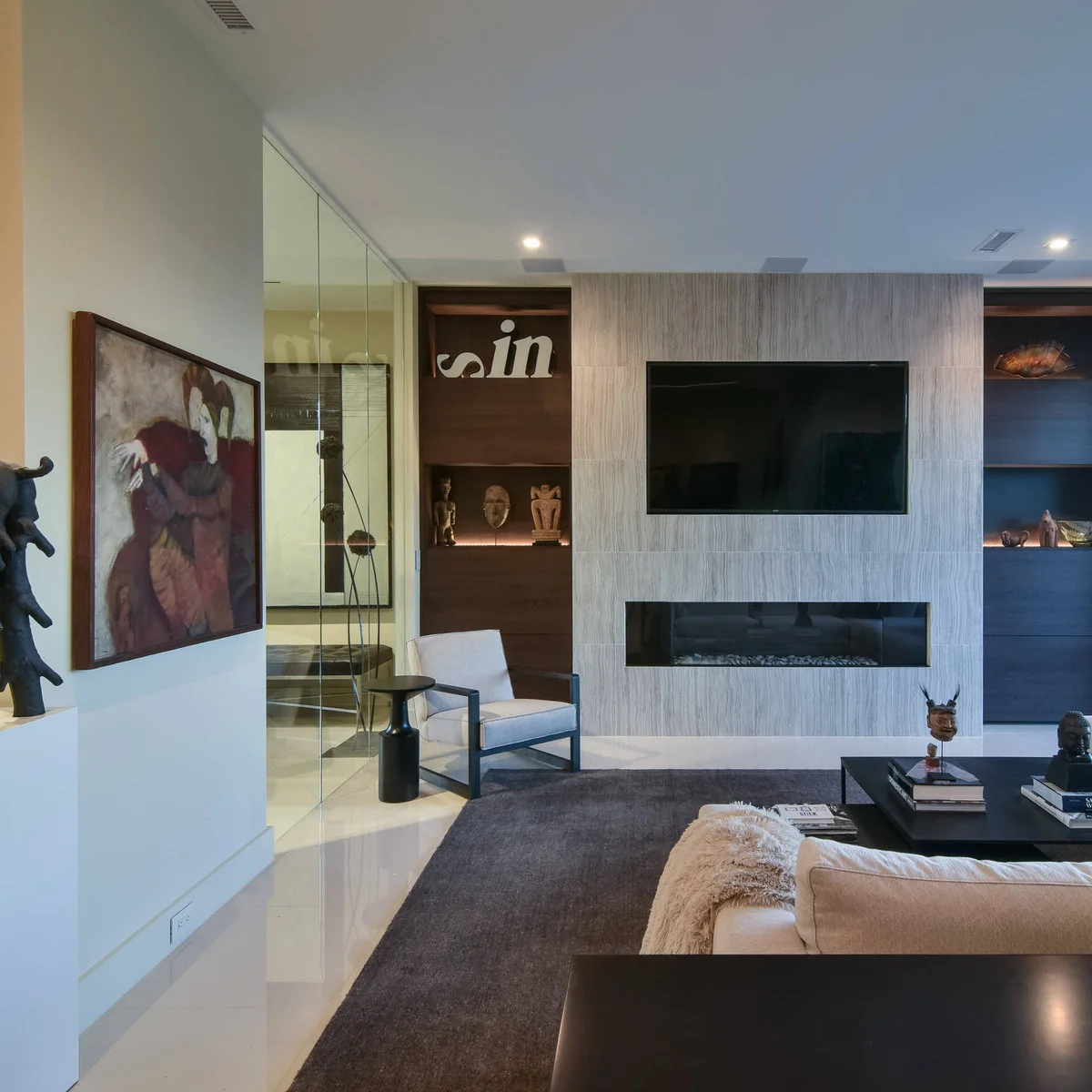 A television and a long narrow fire opening centered on a pale vertically textured wall between dark wood shelves.