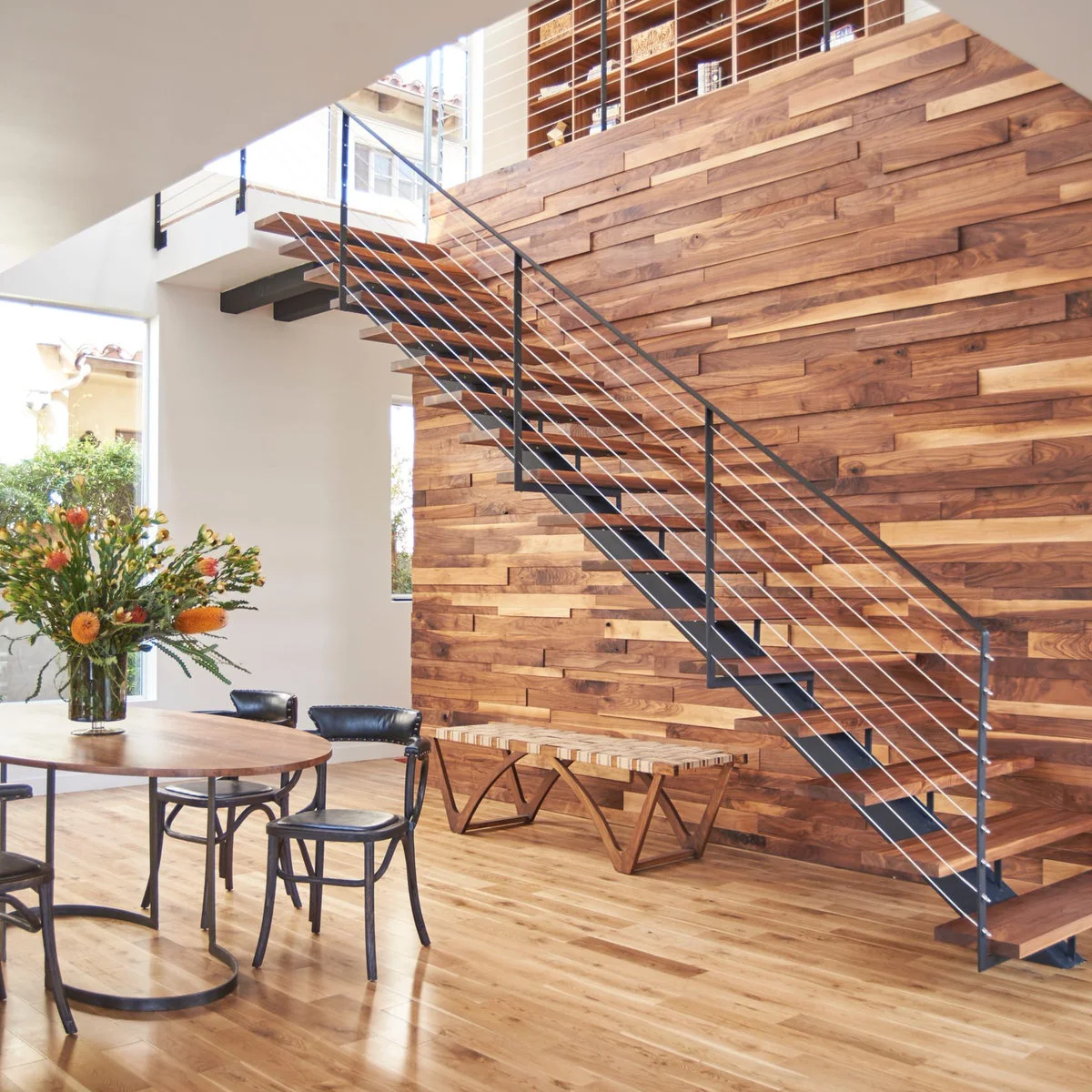 Horizontal wood planks form a textured wall behind an open stair with dark cable railing.