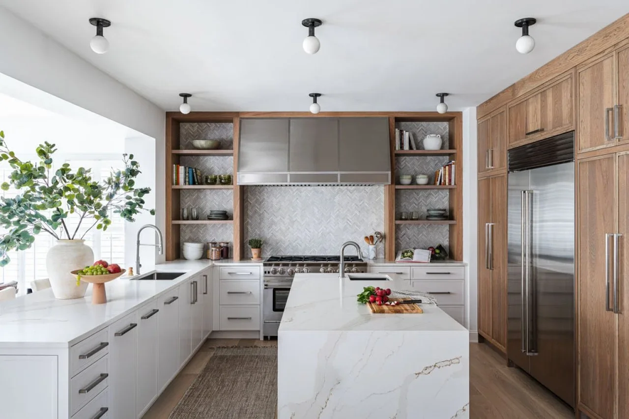 A tall wood cabinet wall frames a refrigerator beside white lower cupboards and wood-framed shelves around a stainless hood.