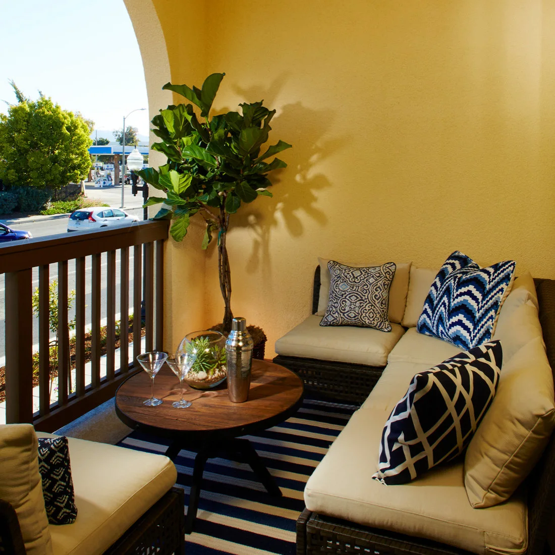 Cream corner seating with blue patterned cushions surrounds a round table on a sheltered balcony