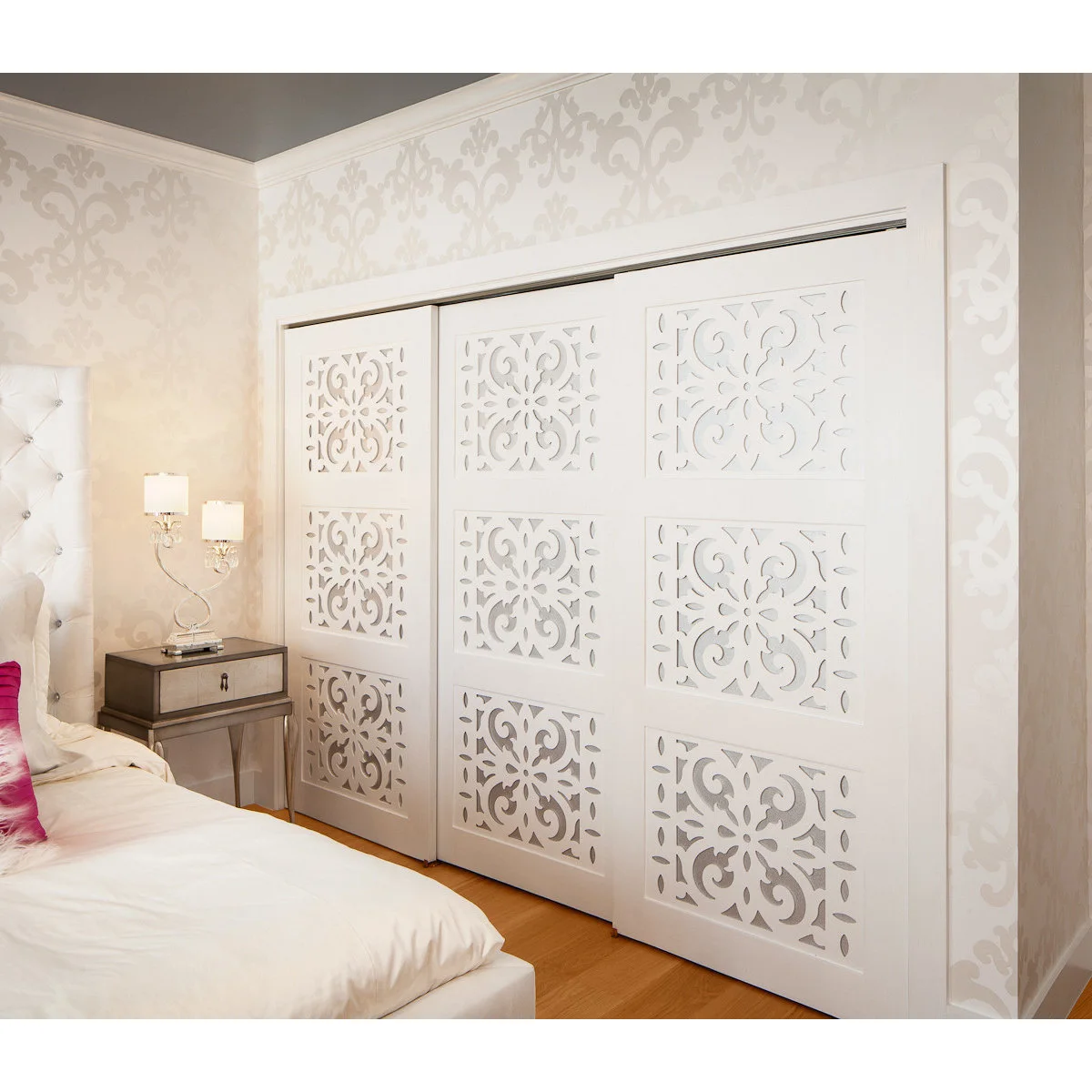 White patterned sliding closet doors beside a pale upholstered bed in a teen bedroom