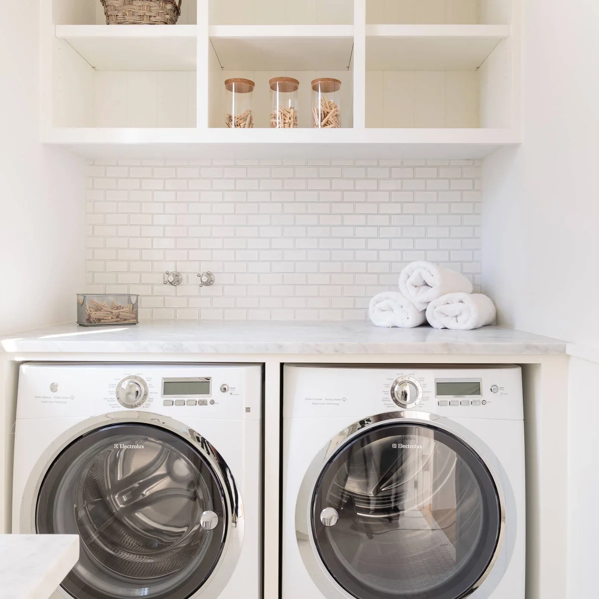 White appliances beneath a pale counter with a white brick-pattern backsplash, upper cubbies and visible wall connections
