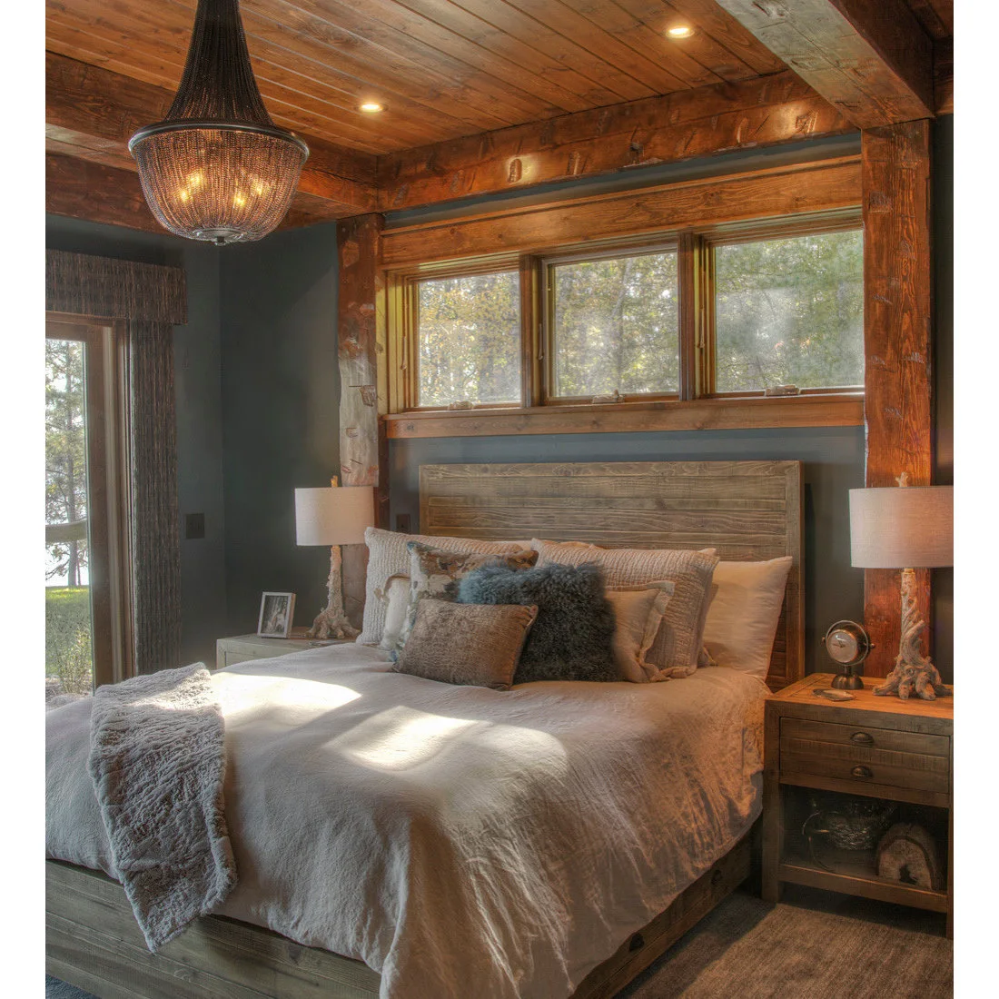A timber headboard and bedside drawers against blue gray walls beneath a wood ceiling
