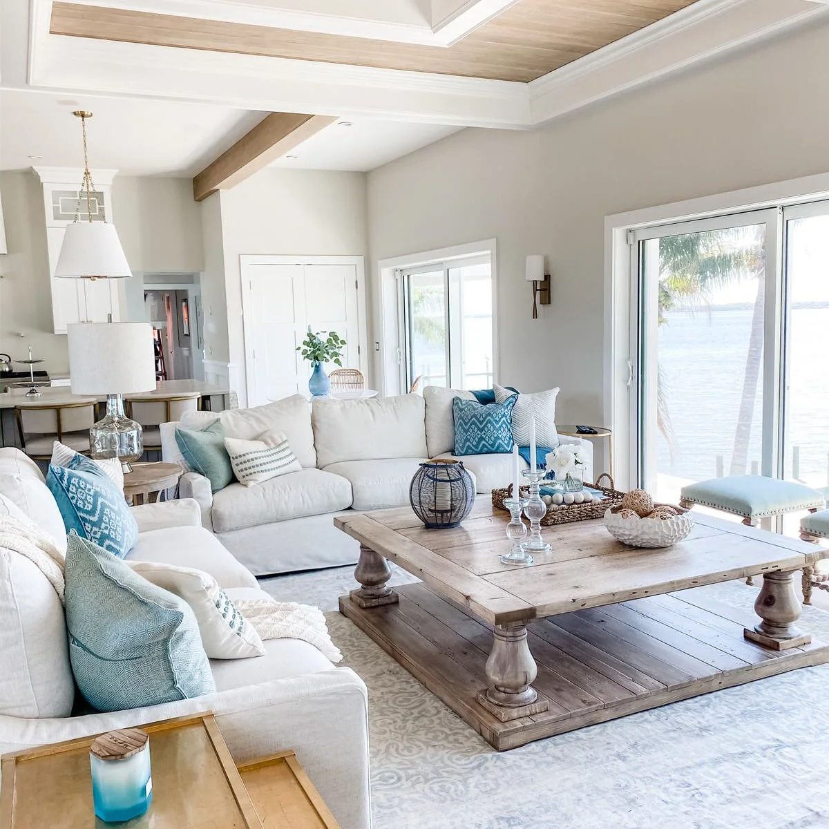 Pale square coffee table with a woven tray, glass holders and a white decorative bowl