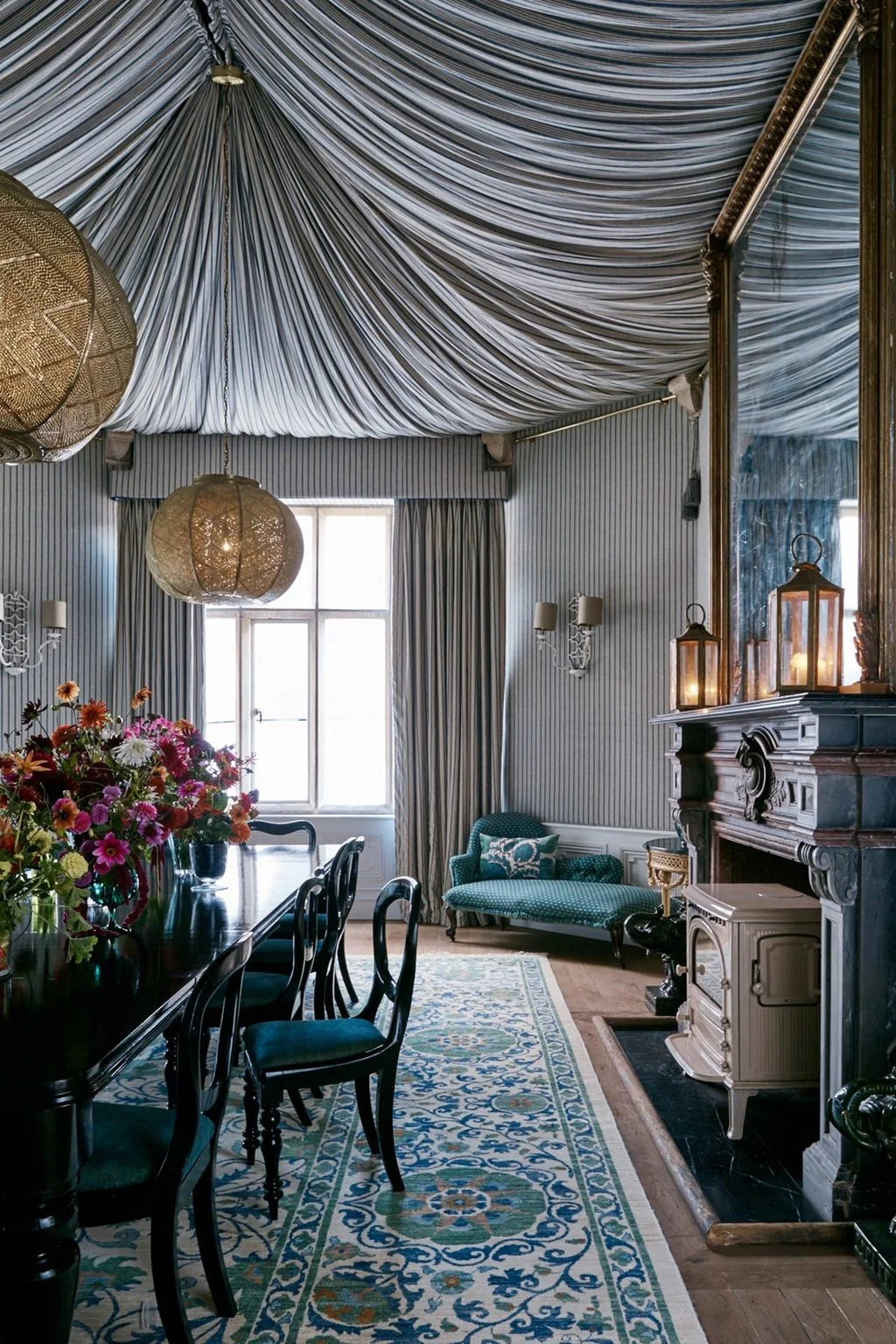 Dining room with fine striped walls and tented ceiling, dark furniture and hanging globe-shaped lights