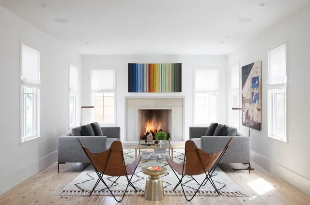 Gray sofas face one another beside tan sling chairs and a pale fireplace.