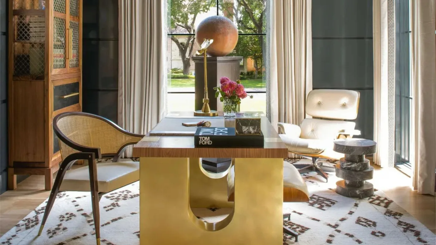 Green office with a wooden desktop on a broad gold-toned base beside tall windows.