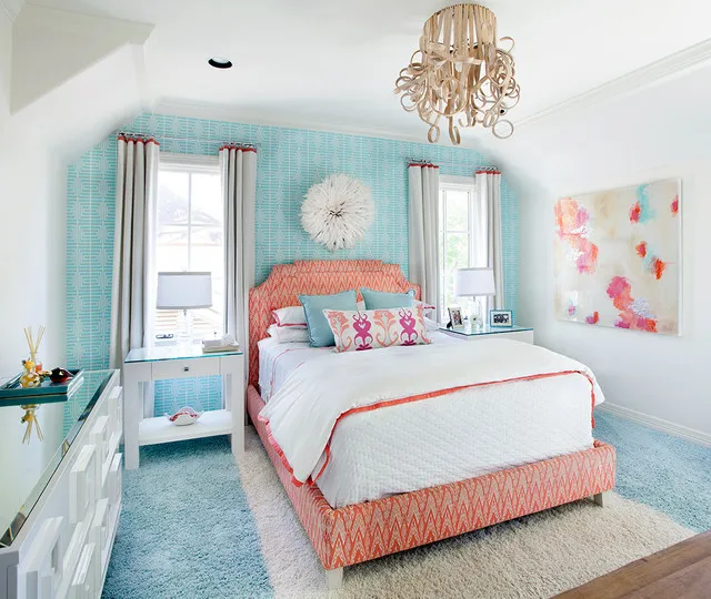 A pale blue patterned wall frames a warm upholstered bed between tall windows.