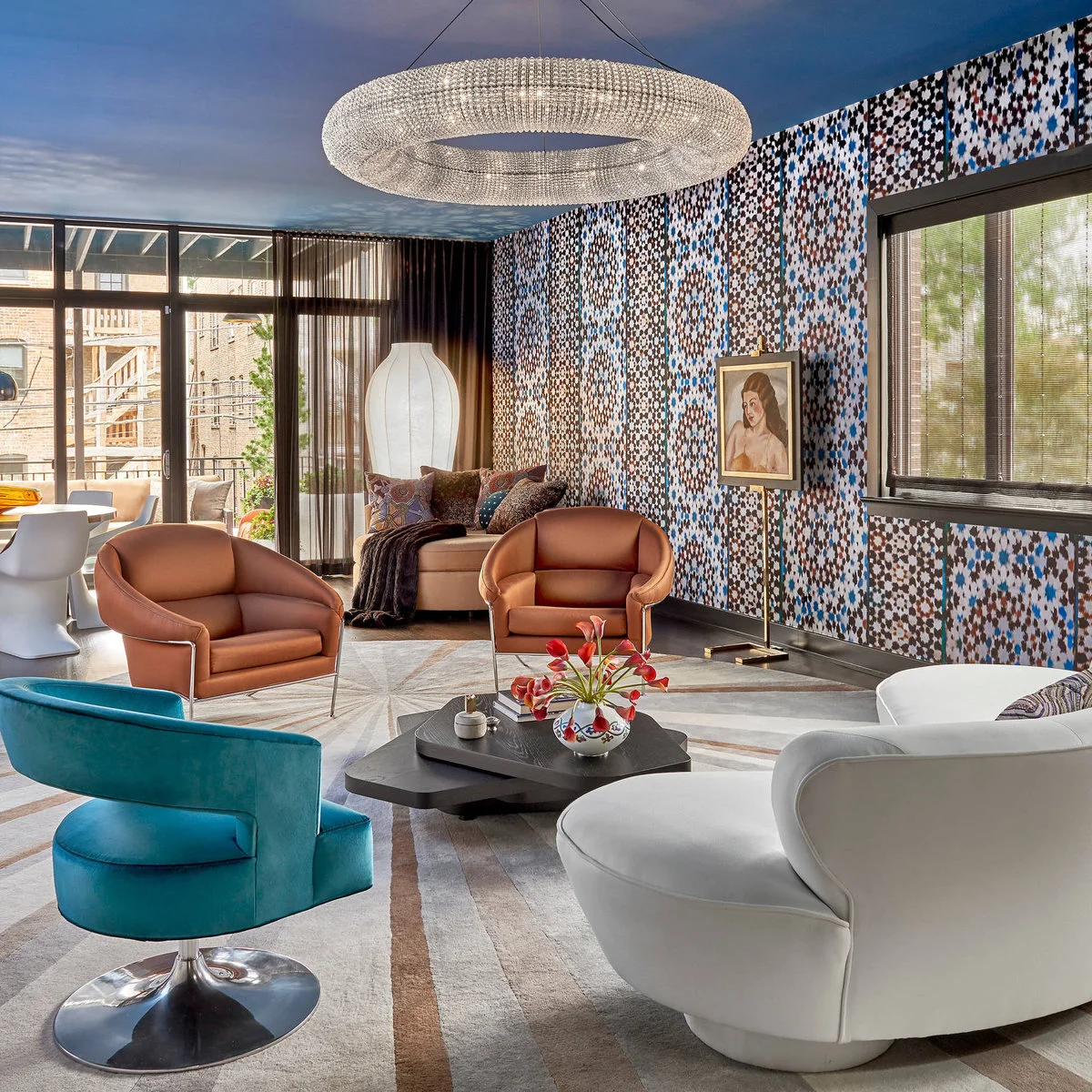A multicolored patterned wallpaper wall stands behind curved chairs, a white sofa and blue ceiling.