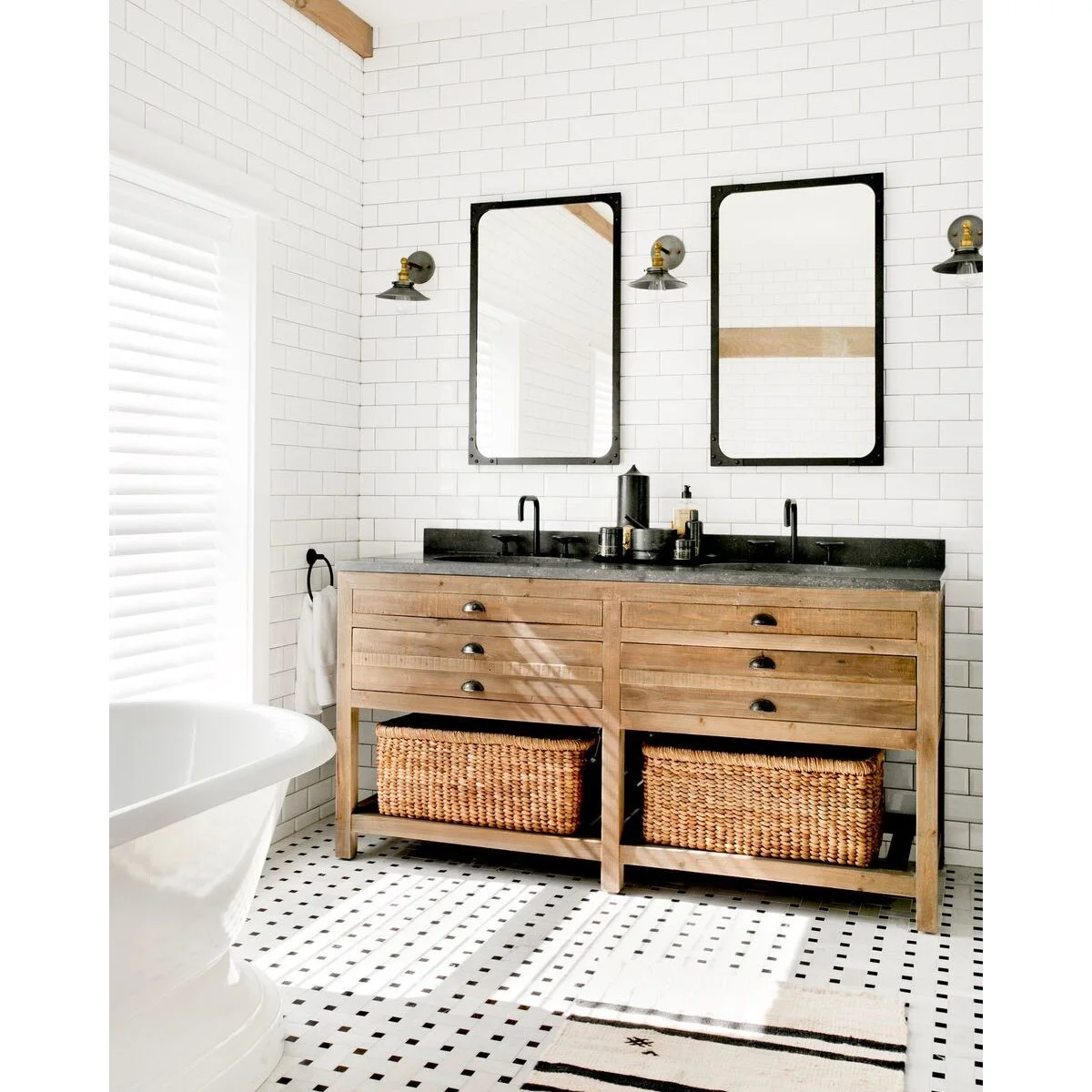 Light wood double vanity with a black counter, small dark accessories and two baskets on the open shelf below.
