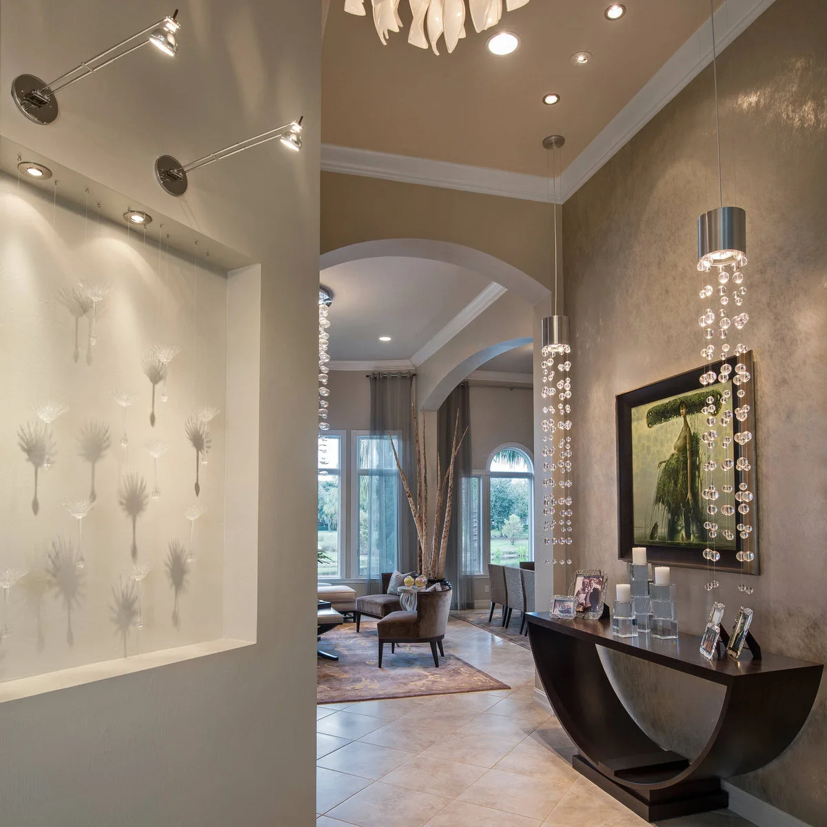 A sculptural dark console beneath framed art and two suspended decorative lights, with family photographs on the table.