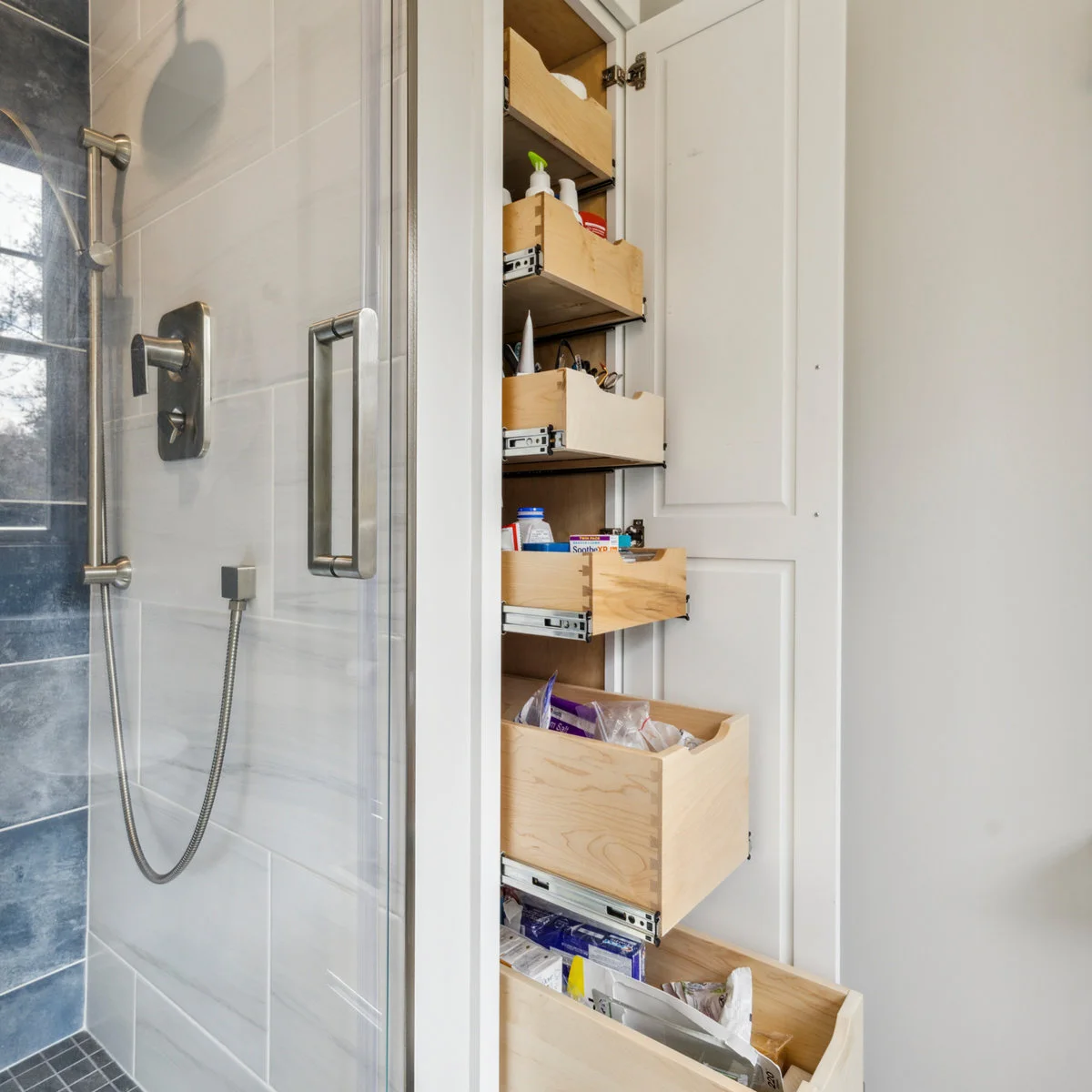 Tall narrow bathroom cupboard with several wooden pull-out storage trays