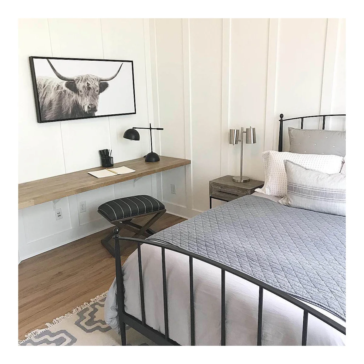 Teen bedroom with a long wall-mounted desk, padded stool and black bed frame