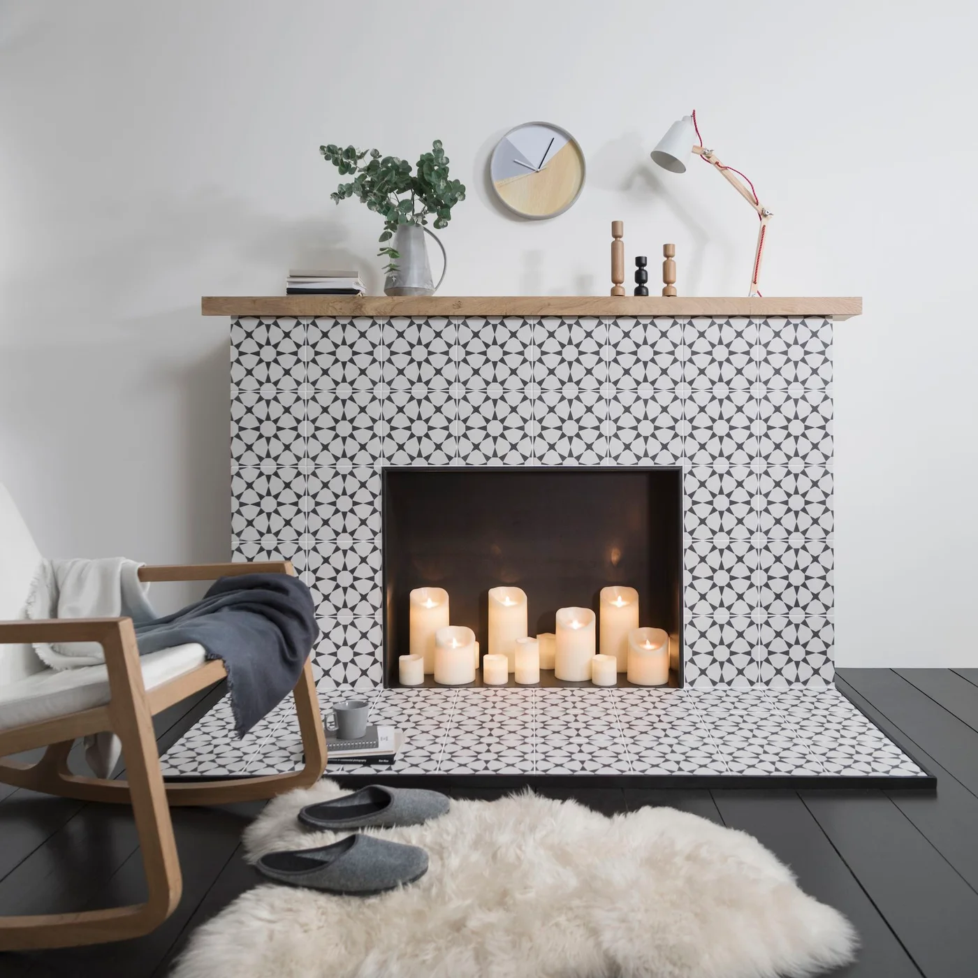 Black-and-white star-patterned tile covers a fireplace face and broad hearth beneath a wood mantel, with decorative candles in the opening.