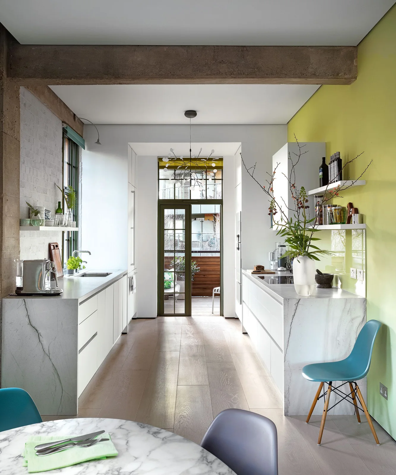 Bright galley kitchen with parallel pale counters, open shelves and a glazed door at the end