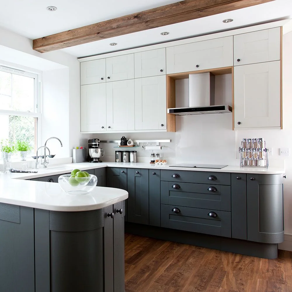 Dark gray lower cabinets and a curved peninsula sit beneath white wall cupboards with wooden edging around an extraction hood
