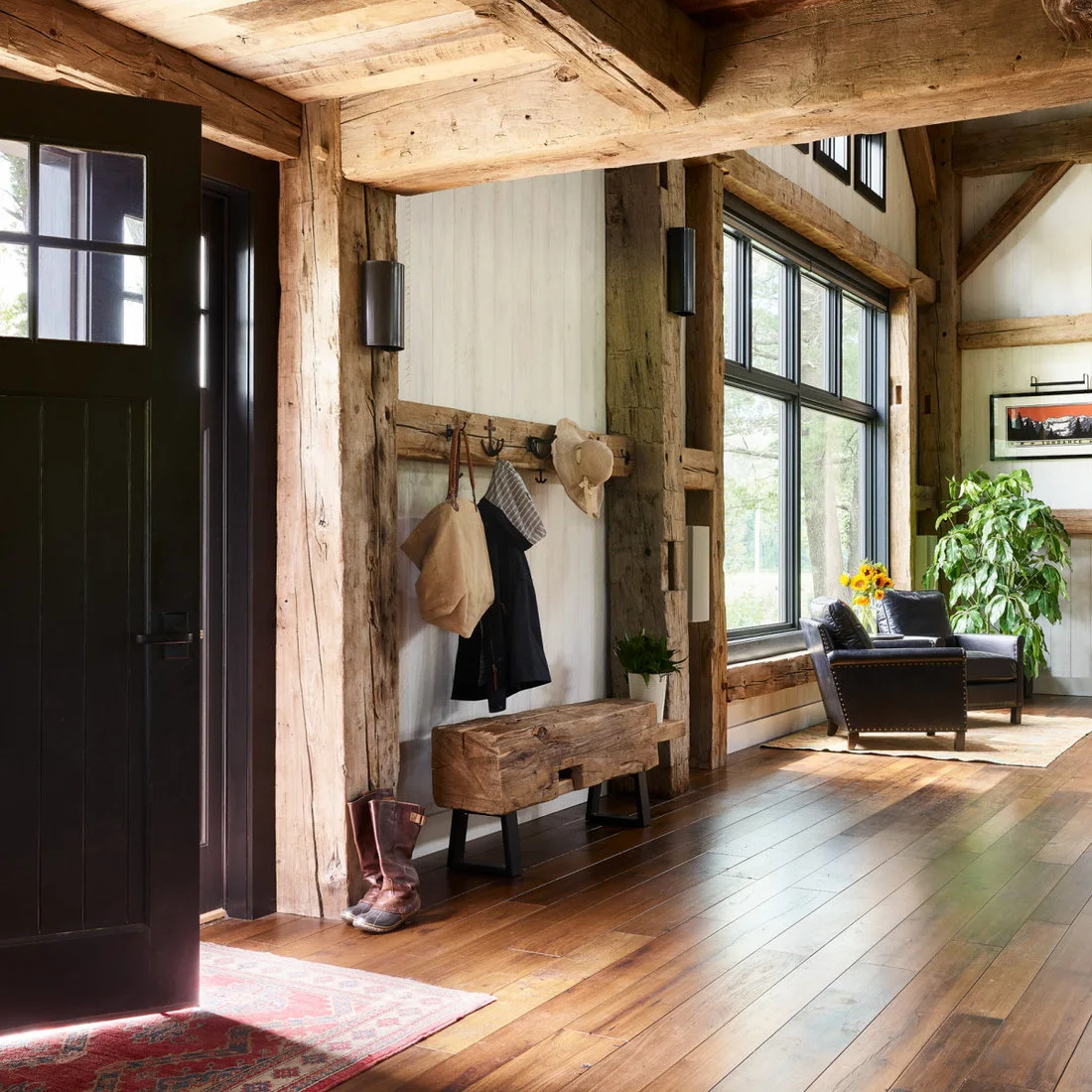 A timber bench and coat rail between exposed posts beside a dark entry door