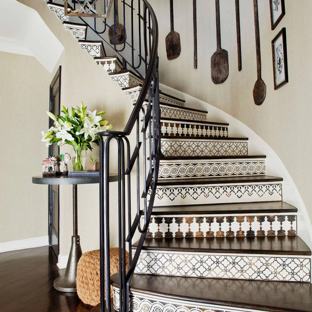 Curved dark wood staircase with varied black-and-white patterned risers and a dark metal rail