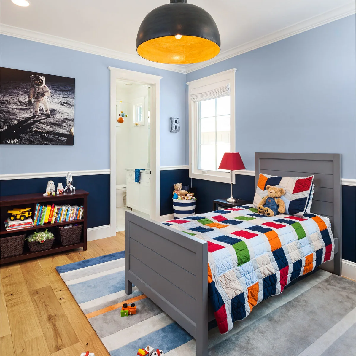 Boy’s bedroom with astronaut artwork, blue two-tone walls and a colorful patchwork quilt