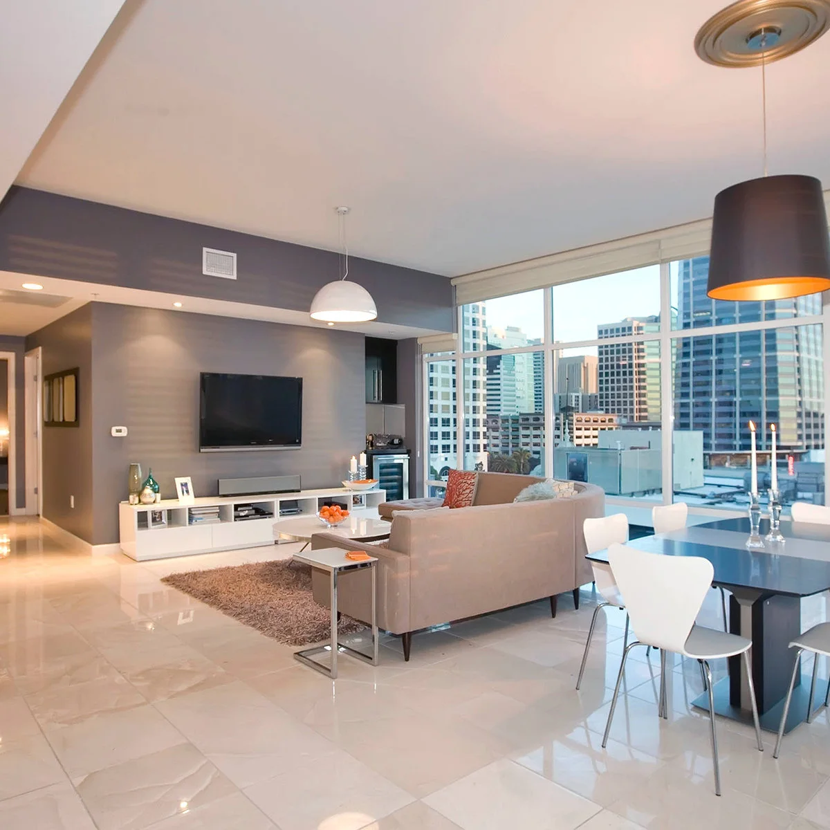 A low white cabinet with open cubbies and lower doors sits beneath a television with a soundbar and small accessories.