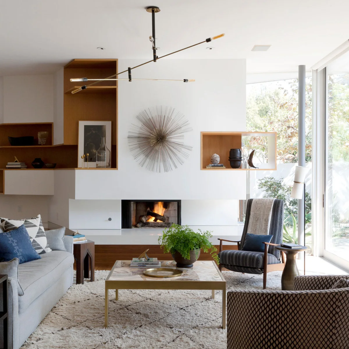 A gray sofa faces a striped high-back chair and a patterned chair around a pale square coffee table.