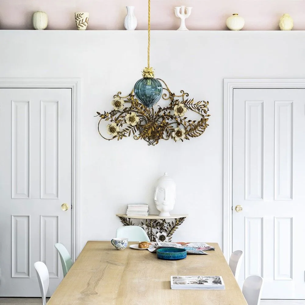 High white floating shelf with pale vases above two doors and a wooden dining table with a decorative chandelier