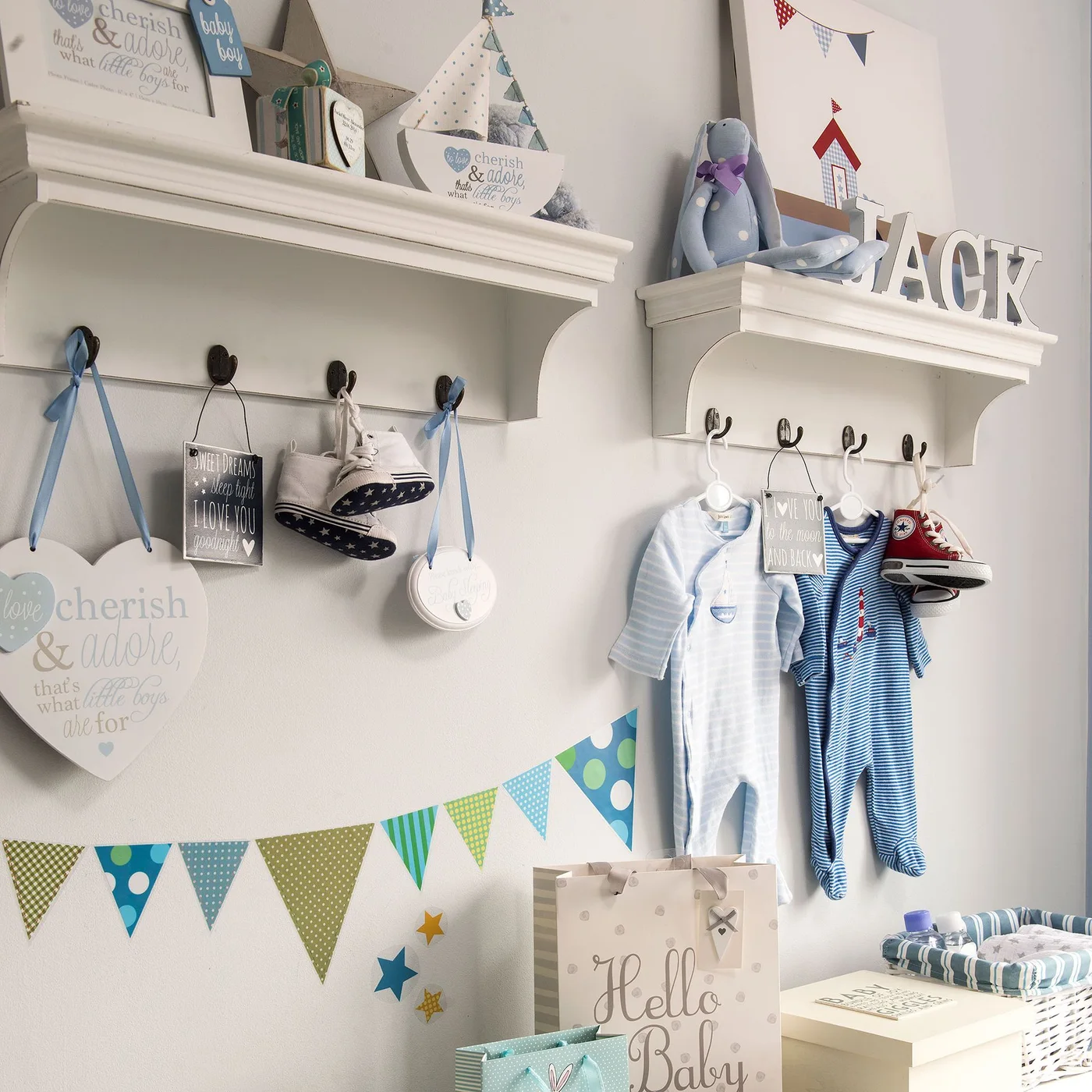 Two white nursery shelves with hooks below hold small clothes, shoes, keepsakes and soft toys.