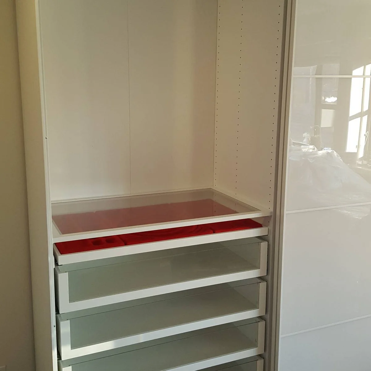 White PAX cabinet with a red-lined divided accessory tray above transparent-front drawers