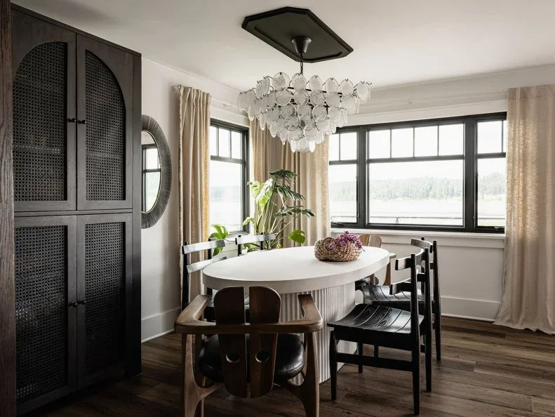Tall dark dining cabinet with patterned doors beside a pale oval table and mixed dark chairs