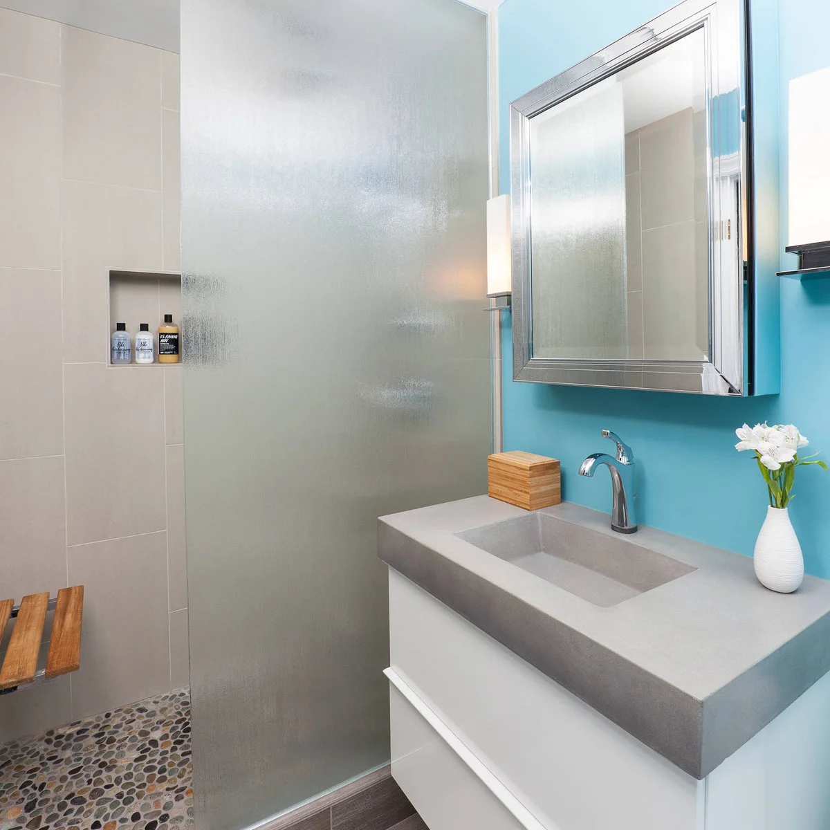 Small bathroom with a frosted shower screen, turquoise basin wall and white drawer vanity