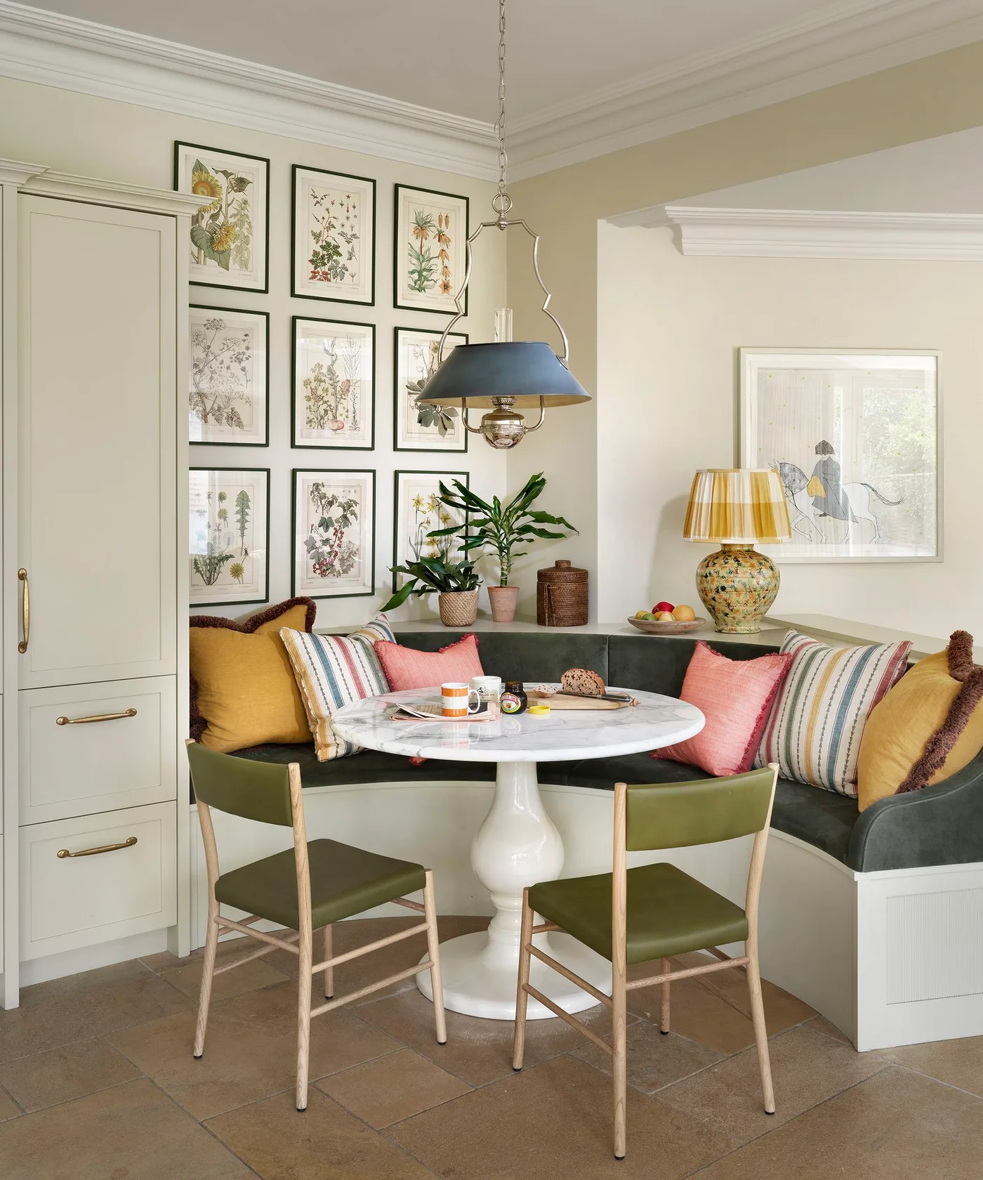 Pale tall cupboard with lower drawers beside a green corner dining bench and a white round table